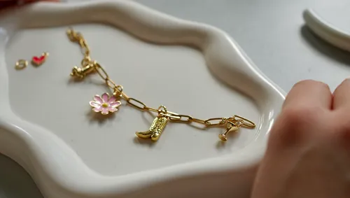 Goldenes Charm-Armband auf einem Tablett.