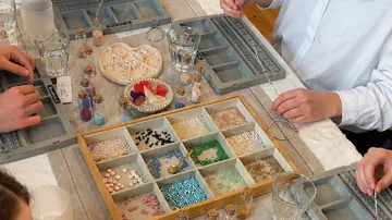 People making jewelry with beads on a table.