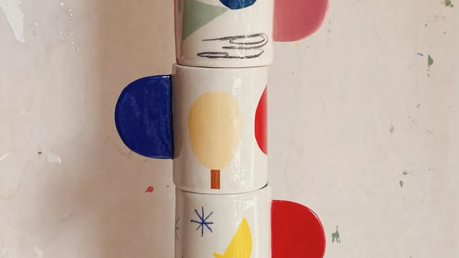 Three stacked mugs with colorful abstract designs.