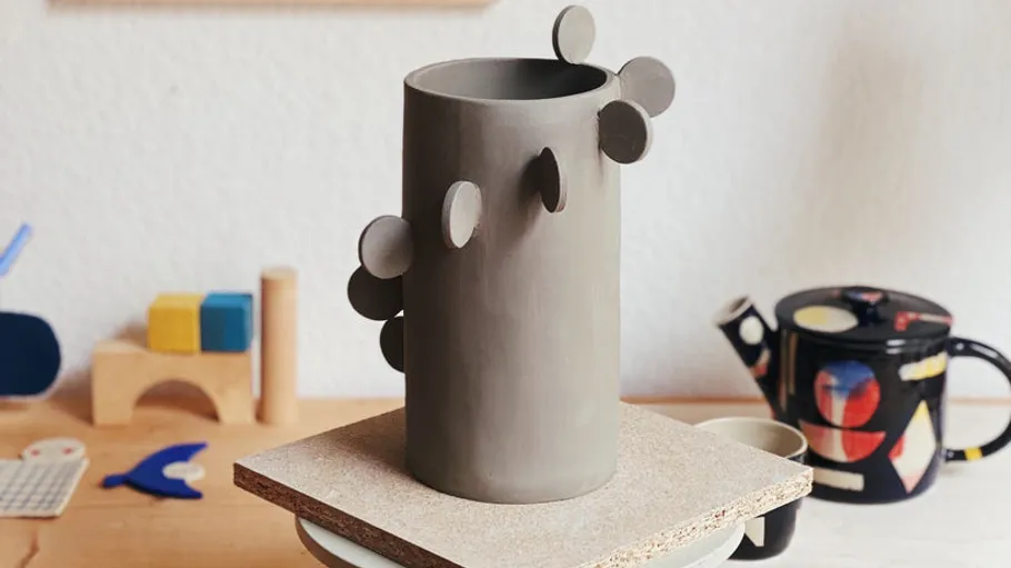 Ceramic vase with round decorations on wooden table.