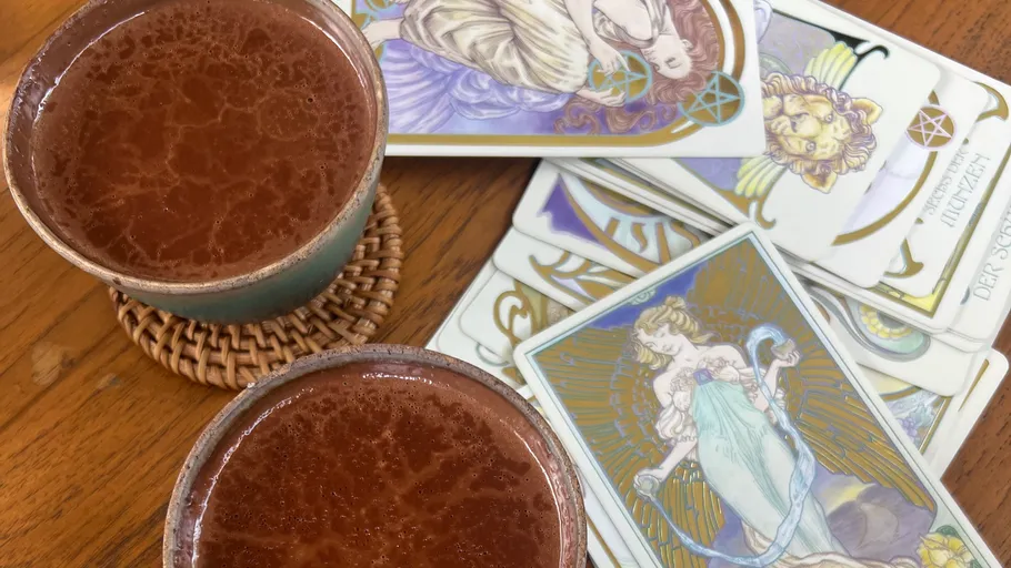 Two cups of cacao next to tarot cards.
