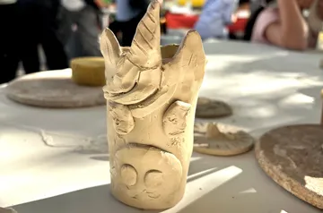 Clay unicorn sculpture on a table outdoors.