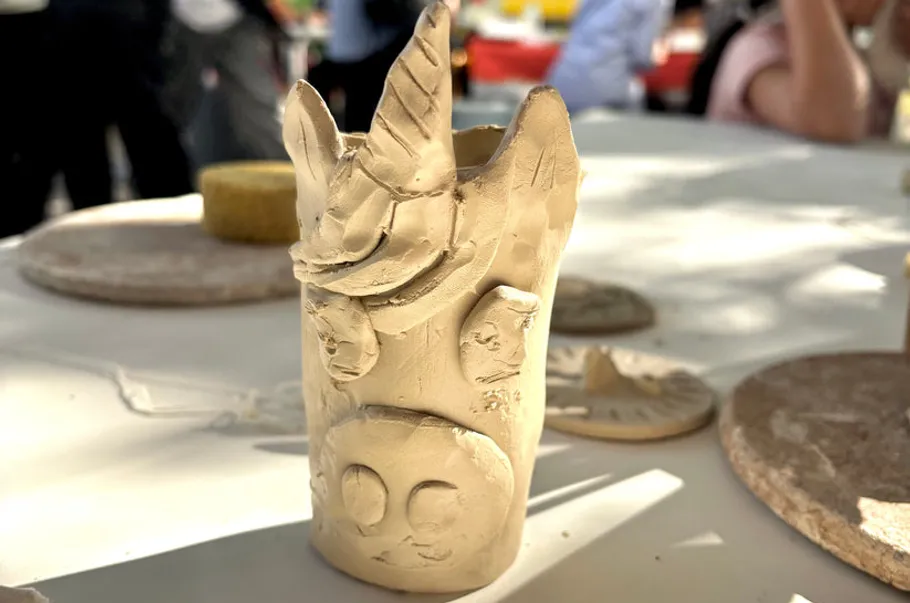 Clay unicorn sculpture on a table outdoors.