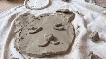 Clay bear face sculpted on cloth surface.