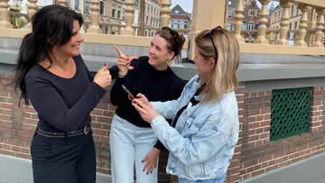 Three women talking happily on a bridge.