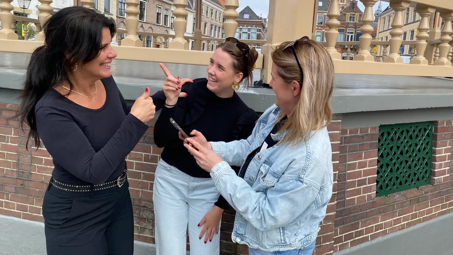 Drei Frauen reden fröhlich auf einer Brücke.