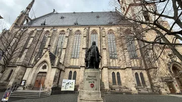 Statue of Bach in front of historic church.