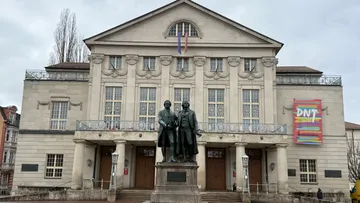 Statue in front of historic theater building.