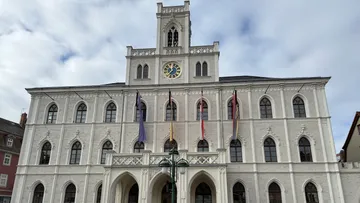 Historic building with clock tower and flags.