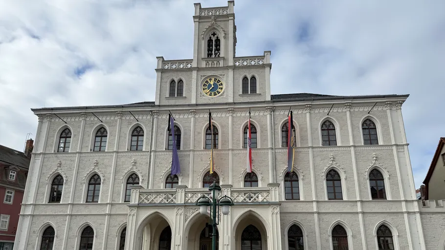 Historisches Gebäude mit Uhrturm und Fahnen.