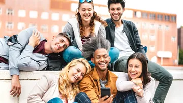 Group of people smiling and looking at phone outdoors.