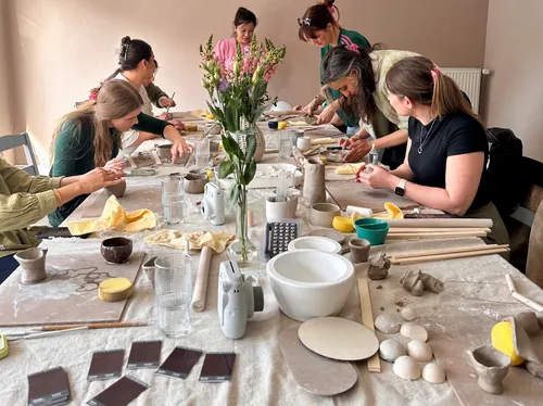 Group crafting pottery at a large table.