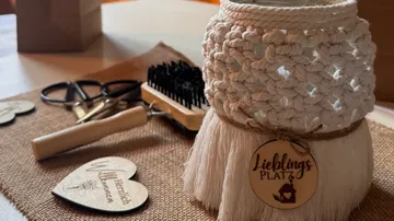 Crocheted pot with tag, scissors, brush on table.