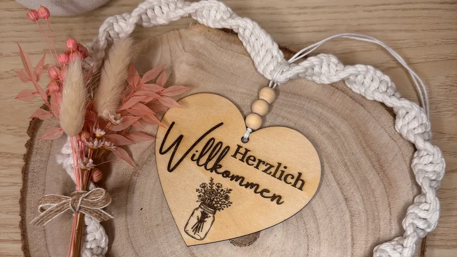 Holzherz mit 'Willkommen' an geflochtener Schnur.