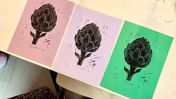 Three black artichoke prints on colored paper.