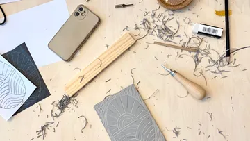 Carving tools and phone on messy desk.