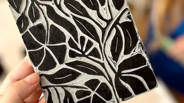 Hand holds black-and-white leaf pattern print.