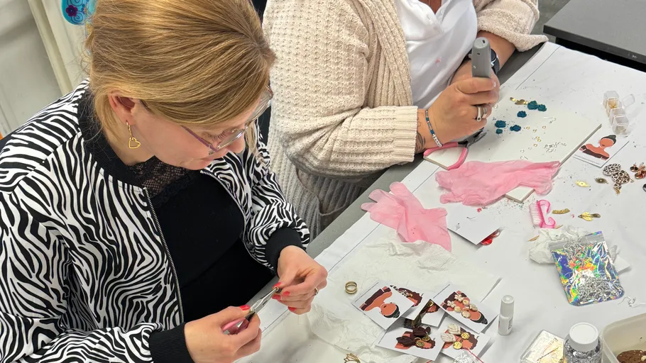 Two women crafting jewelry at a table.