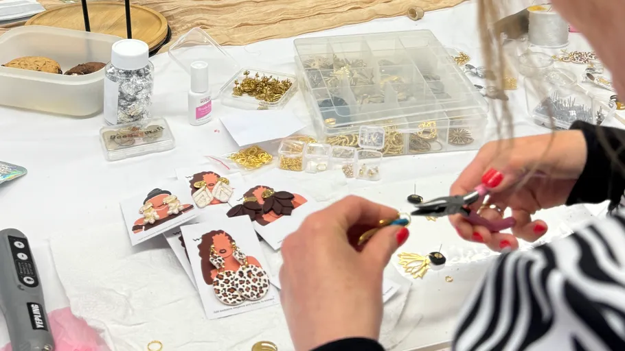 Person crafting jewelry at a cluttered table.