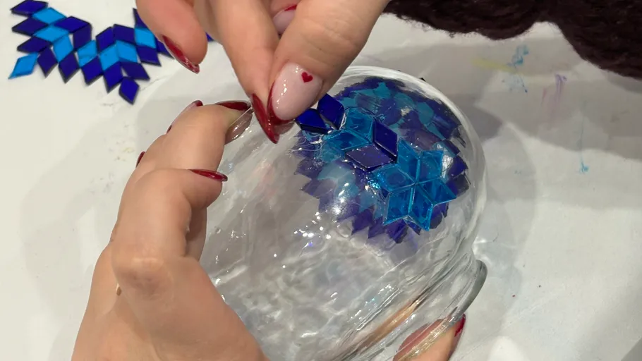 Hände dekorieren Glasschale mit blauen Fliesen.