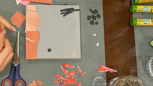 Hände arrangieren Papier auf grauer Leinwand.
