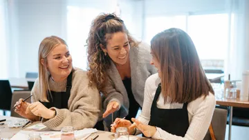 Drei Frauen malen zusammen in einem Raum.
