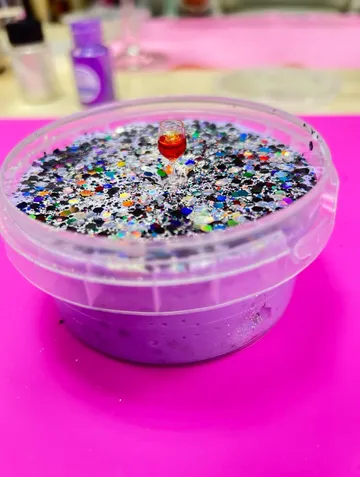 Purple slime in container with colorful glitter.