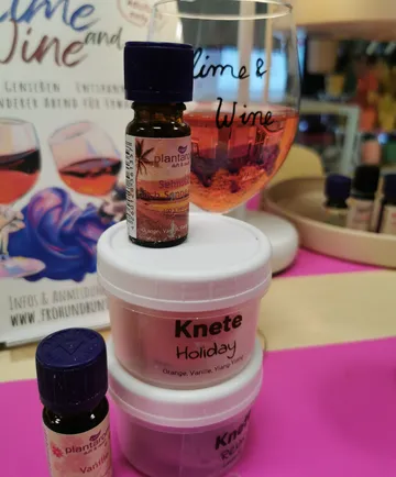 Aromatherapy oils and putty next to wine glass.