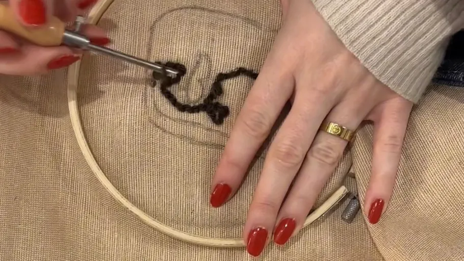 Person embroidering a pattern on fabric.