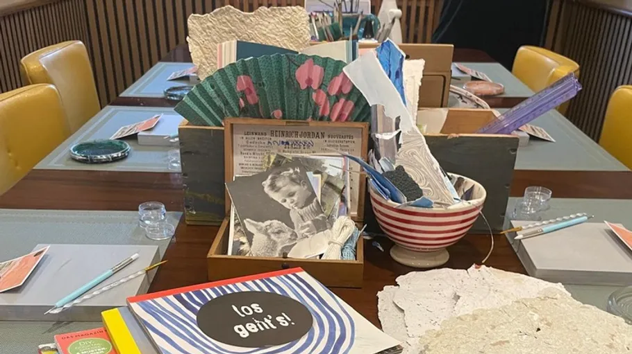 Basteltisch mit Kunstmaterialien, Büchern und Papier.
