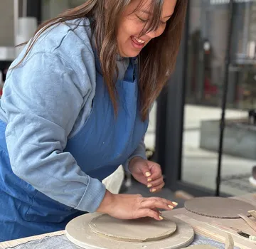 Frau fertigt Keramik im Innenbereich an.