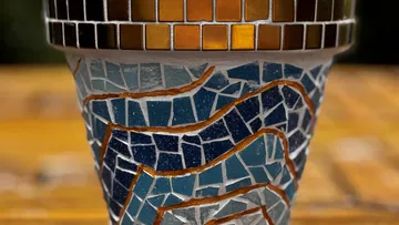 Mosaic flower pot with colorful patterns outdoors.
