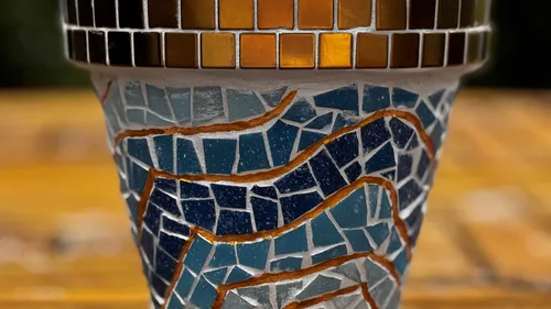 Mosaic flower pot with colorful patterns outdoors.