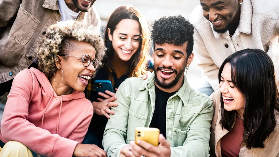 Gruppe von Freunden lächelt auf Smartphone im Freien.