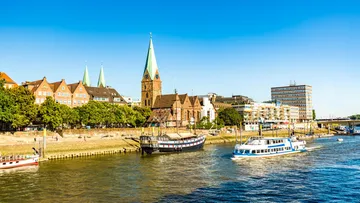 Boats sailing on river by historic buildings.