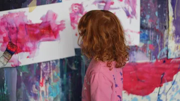 Kind malt bunte abstrakte Kunst drinnen.
