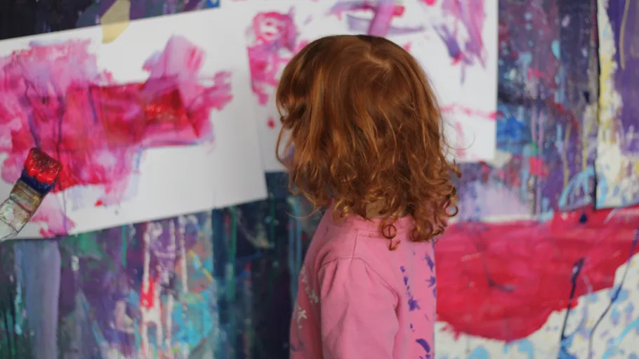Kind malt bunte abstrakte Kunst drinnen.