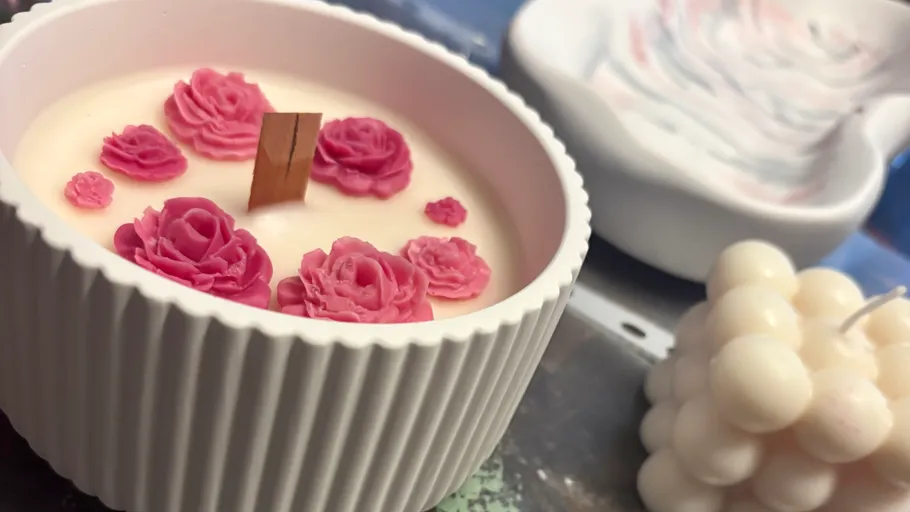Decorative candle with pink roses in dish.