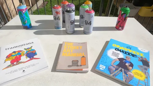 Spray paint cans on table with graffiti books.