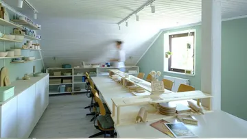Kunststudio mit Tischen und Regalen, Person unscharf.