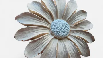 Wooden flower sculpture with white petals.