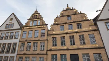 Historic buildings with ornate facades, cloudy sky.