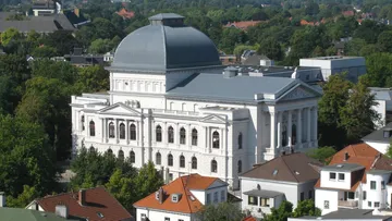 Large white classical building surrounded by trees.
