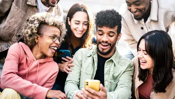 Group of friends looking at phone outdoors.
