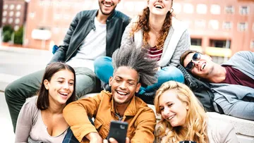 Gruppe von Freunden lacht, Selfie draußen machend.