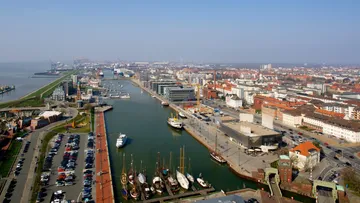 Hafen mit Booten und Stadtsilhouette, sonniger Tag.