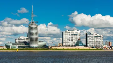 Moderne Gebäude an einem Fluss mit Wolken.
