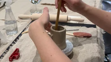 Hände formen Ton auf einem Tisch.