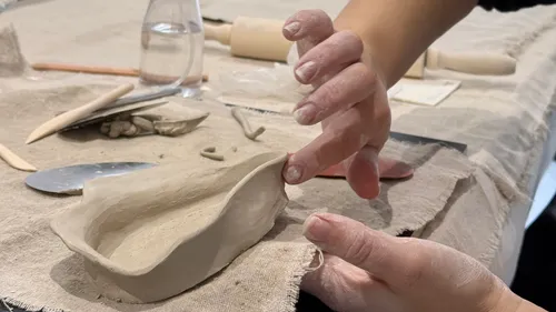 Hands shaping clay on a table.