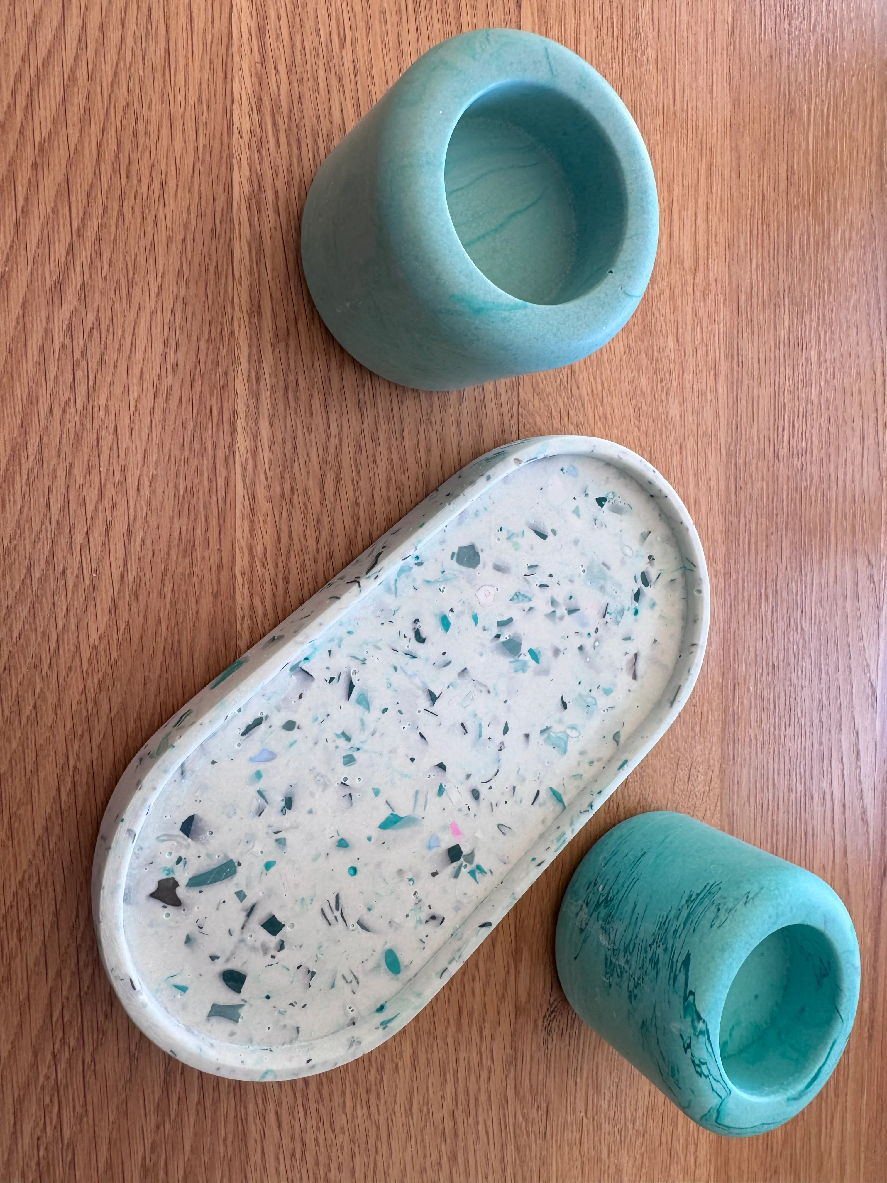 Zwei türkisfarbene Becher und Terrazzo-Tablett auf Tisch.